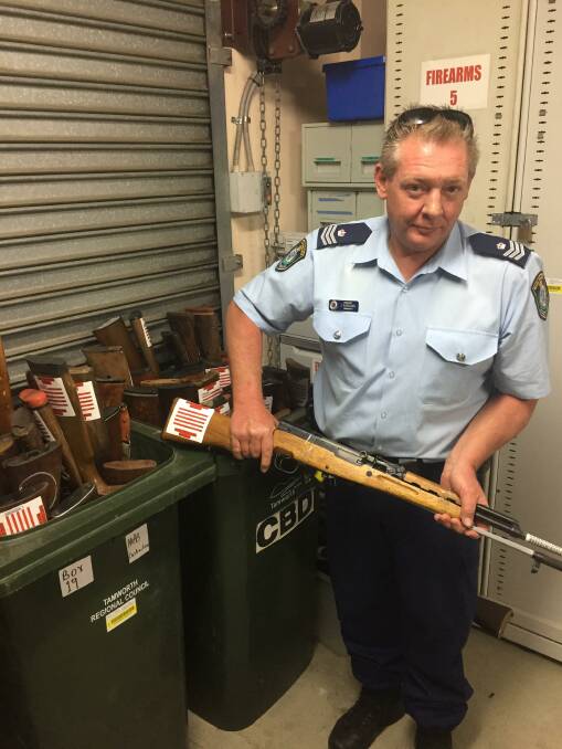 Gun ho: Oxley Sergeant James Parsons examines some of the firearms including shotguns and long-arms that have been surrendered in the gun amnesty.