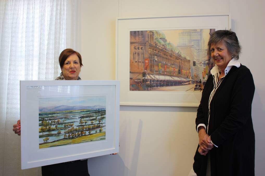 Gunnedah artist Shirley Urquhart with a watercolour she painted recently of the flooding from Porcupine Lookout. She is pictured here with Work of Art Community Gallery coordinator Philippa Murray and a watercolour of George Street, Sydney, by artist Julie Simmons. Both works will be included in the Watercolours exhibition.
