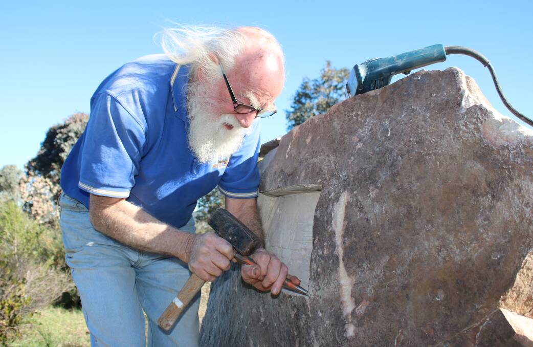 HANDS-ON: Uralla sculptor Carl Merten prepares a section on a rock at Pensioners Hill for the plaque honouring Ned Iceton. Mr Merten designed the bas-relief plaque, which is made out of bronze.