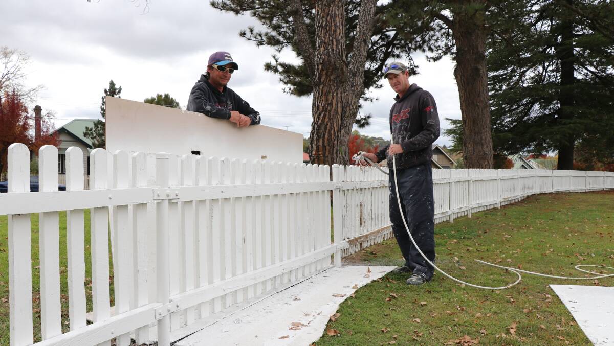 Adam Stackman and Nathan Stace at work painting Lambert Park fence.