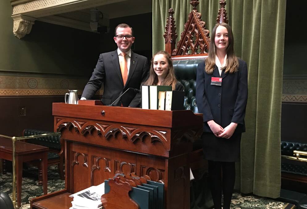 Northern Tablelands Junior MPs pictured with their ‘senior’ colleague Adam Marshall around the Speaker’s Chair in the Legislative Assembly, Caitlin Schuman, centre, and Gemma Weguelin.