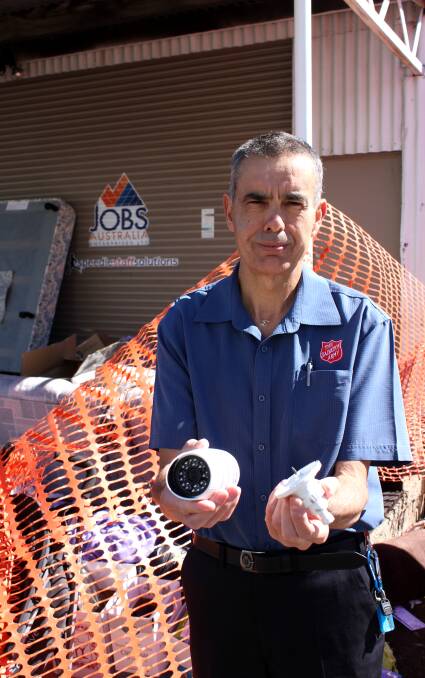 Captain Dale Murray from the Armidale Salvation Army holds the CCTV camera that was ripped from the wall near the collection bins over the weekend.