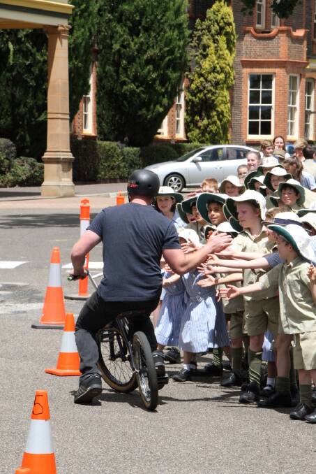 RIDE ON: Cam White gives students a quick high five before flipping out the front of the school.
