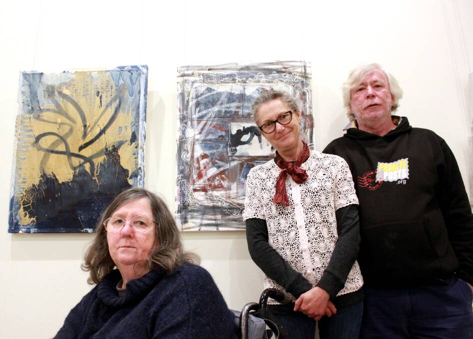 Artists Jenny Beattie and Janet Reid with project coordinator Ned McDowell in front of two artworks by Janet Reid on sale at the exhibition.