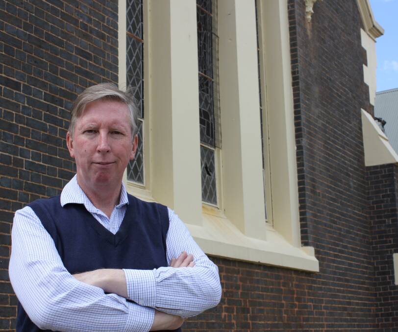 Reverend David Seaman stands outside the Presbyterian Church where vandals have damaged the windows. The offenders later set fire to a bush in Central Park.