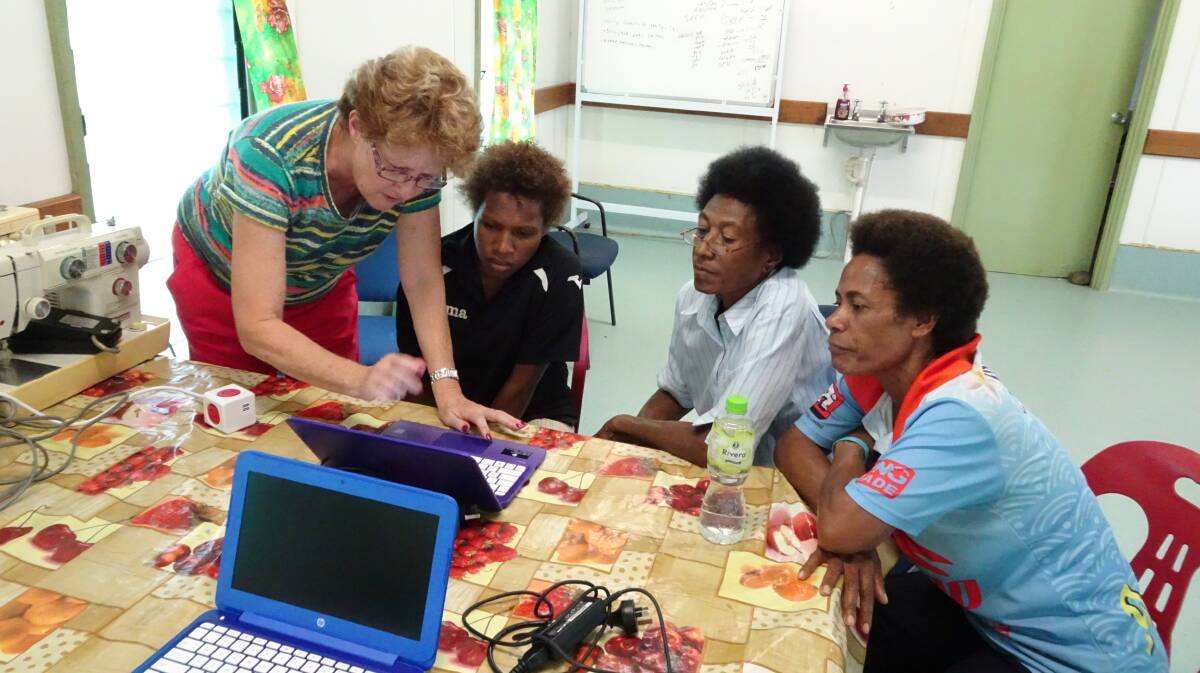 Sue Moran tutors Kokoda locals on computer use during the visit.