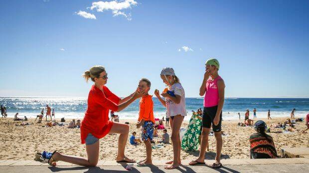 Kate Swift and her three children Carter, 5, Willow, 7, and Finn, 9, apply sunscreen at Coogee Beach. Photo: Katherine Griffiths
