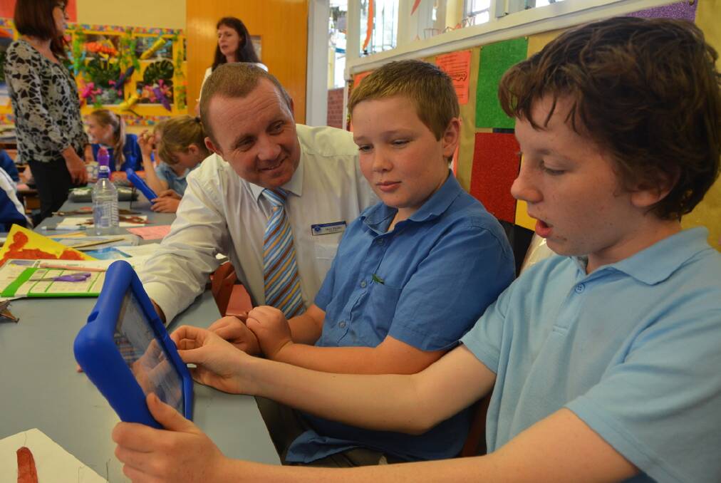 LOGGED ON: From left, Principal Matt Hobbs helps Bailey Eather and Cody Cheeseman with their lessons using an iPad.