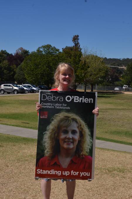 Daisy O'Brien helps out her mother Debra by handing out how-to-vote Labor cards at the Ben Venue polling booth.
