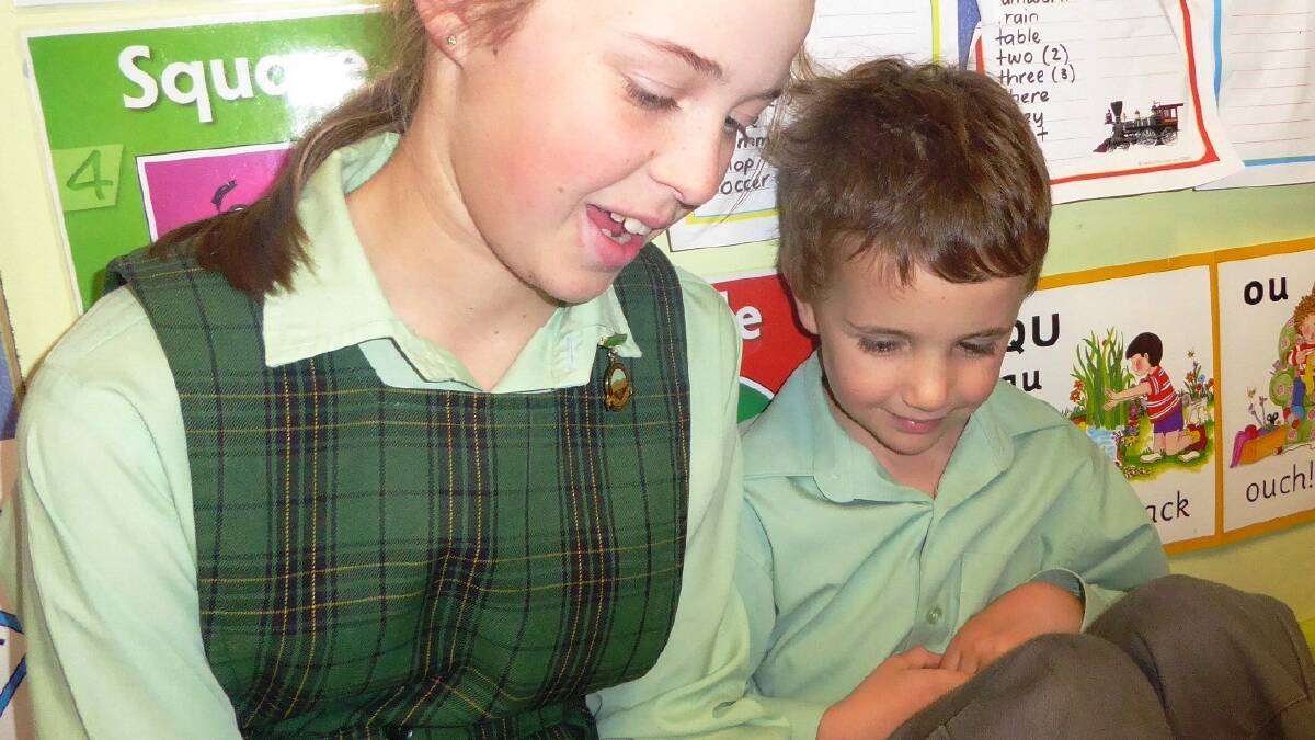 READ BETWEEN THE LINES: Year 6 student Caitlin Bell shares her love of reading stories with kindergartner Angus Youman.