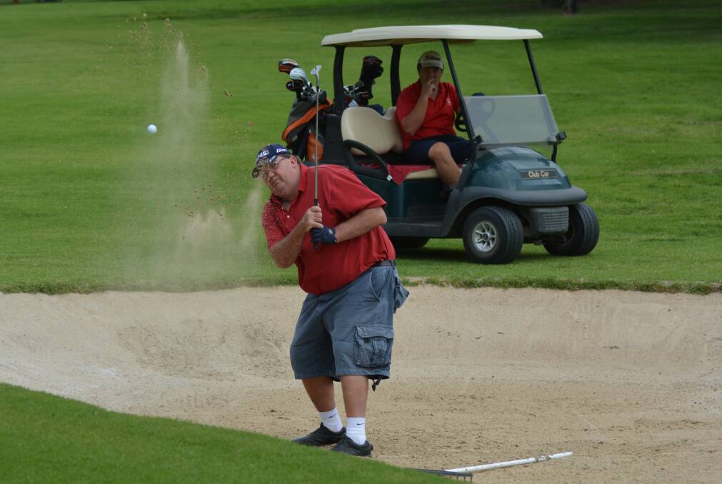 GETTING OUT OF TROUBLE: Bill Turner blasts one out of the bunker during the Back to Armidale Easter Golf Carnival as his playing partner looks on. The carnival attracted more than 300 players to the club.