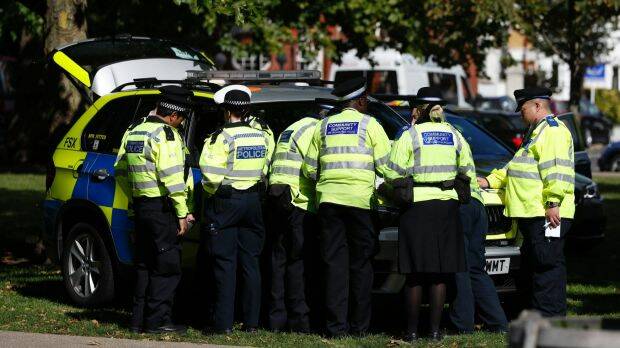 Police and community support officers gather round a police vehicle near where the incident happened. Photo: AP