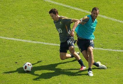 No rest for the Roos ... Matt McKay and Carl Valeri tussle for the ball at Socceroos training in Doha.