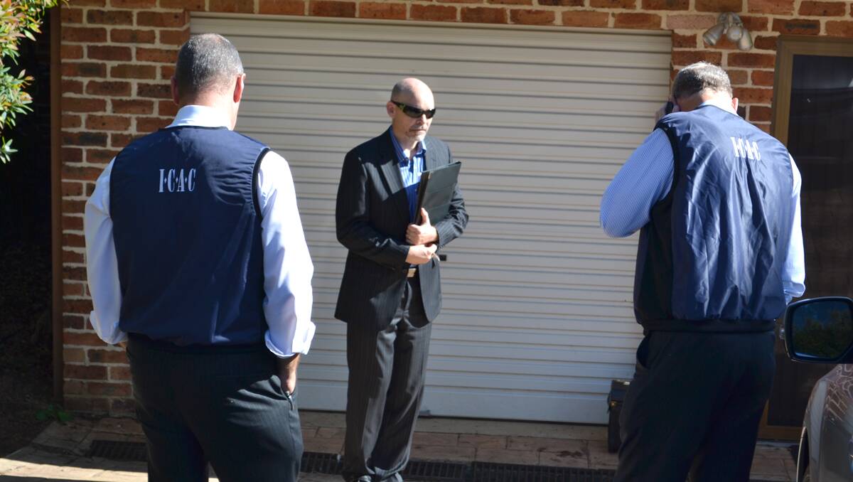 Men wearing ICAC vests outside Richard Torbay's house on Wednesday morning.