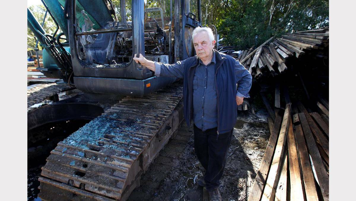 Scenes from an arson attack at Iacconi Earth Moving and Demolition, Redhead. Business owner Mik Illet next to the burnt out earth mover. Picture Jonathan Carroll, Newcastle Herald