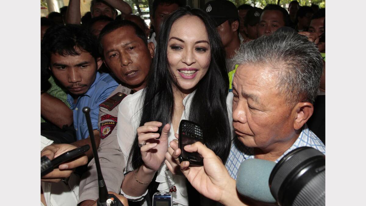 SPOTLIGHT: Former Armidale student Angelina Sondakh is escorted out of an Indonesian court by her father “Lucky” Sondakh, right, who also studied at Armidale.