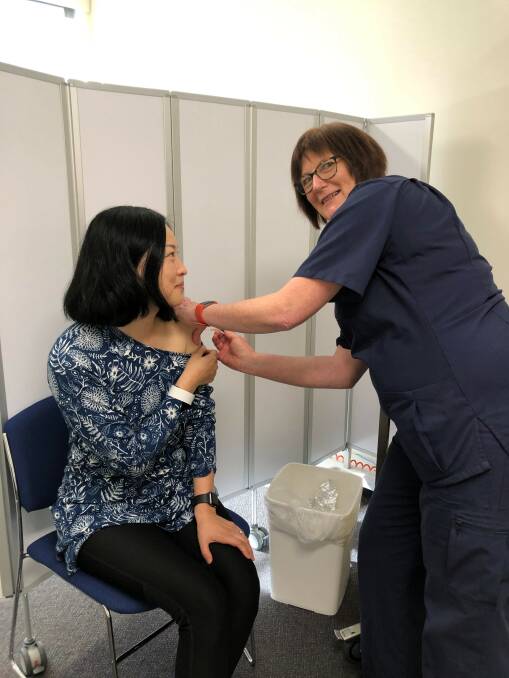 Zunjie Wu receiving her vaccination from nurse Helen Yeates at Armidale Hospital.