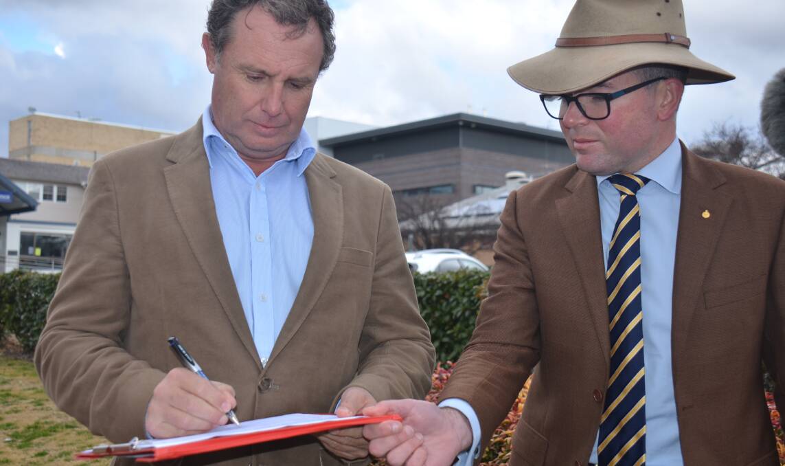 Armidale mayor Sam Coupland signs the petition on Tuesday alongside Northern Tablelands MP Adam Marshall. Picture: Laurie Bullock