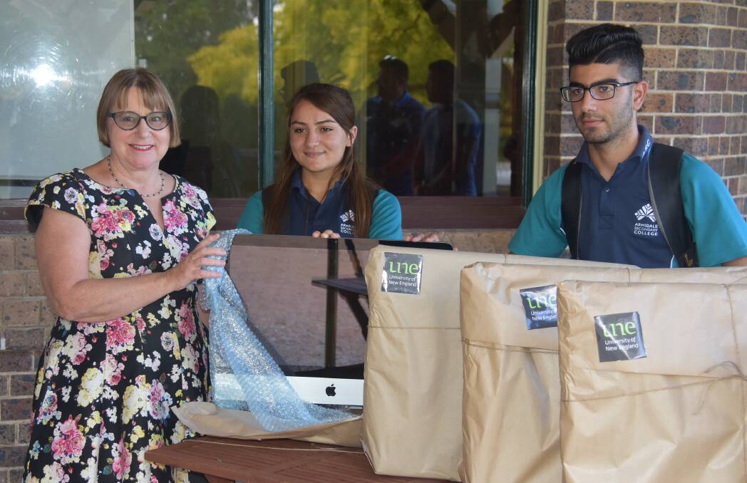 APPLE-TIZING: UNE's then vice-chancellor Professor Annabelle Duncan hands over computers donated by the university to Ezidi students Ashan Jarallah and Rami Simoki. Photo: Nicholas Fuller