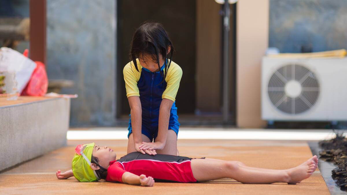 A young woman does CPR on a little boy