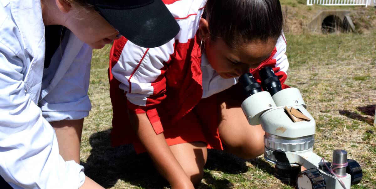 Drummond Memorial Public School student Leikiesha Weatherall learning about soil with a member of the UNE Discovery Bus in collaboration with Landcare for National Science Week.