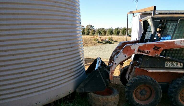 An Arding resident tilting a household water tank to get the remaining water 