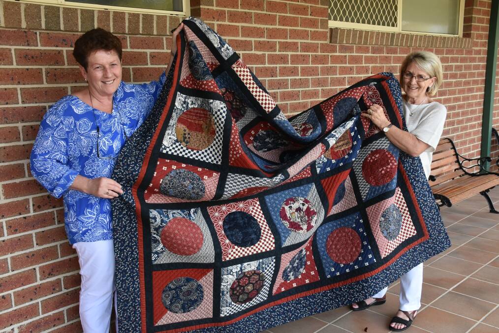 CREATIVE: Quilters and patchworkers of New England members Jennifer Richards and Robyn Wood with the quilt that will be raffled for BackTrack. Photo: Nicholas Fuller