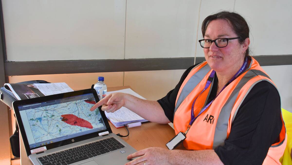 STAYING ALERT: Council staff member Sally Schofield shows the predicted spread of the fire, at the Guyra Showgrounds information hub. Photo: Nicholas Fuller