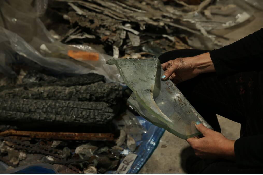 Fiona Lee looking at a piece of melted glass from her bushfire-destroyed home. Picture: Simone De Peak