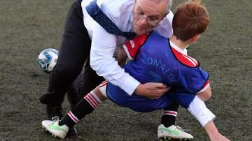 Prime Minister Scott Morrison tackles Luca Fauvette on a soccer field in Devonport on Wednesday.