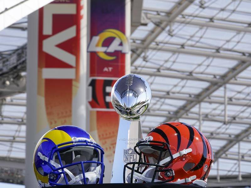 The NFL's Vince Lombardi Trophy, flanked by Los Angeles Rams and Cincinnati Bengals helmets.