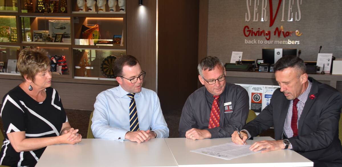 Armidale Golf Club's Jane Sharpe , Member for Northern Tablelands Adam Marshall, and CEO Armidale ex-Services Club Scott Sullivan watch the manager of Armidale Bowling Club, Walter Sauer, put the last signature to the MOU document.