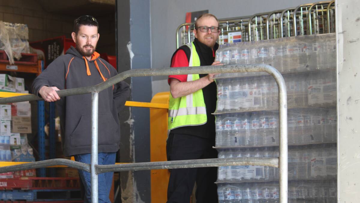 DONATIONS: Greg Cameron from Allingham's Removals and Storage helps Coles grocery manager Brent Selway load two pallets of bottled water, nappies and other essential items onto a truck. 