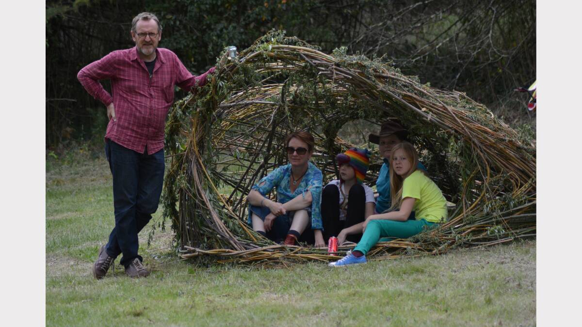 Uralla artist Andrew Parker with his gunyah. Claire Blakester, Shenoah Fisher, Jaz Blakester and Emily Bloomfield test out the traditional Aboriginal shelter.