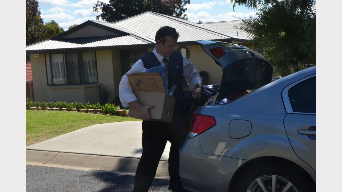 HEAVY LIFTING: Two ICAC investigators retrieve boxes from a car before transporting them to another vehicle.